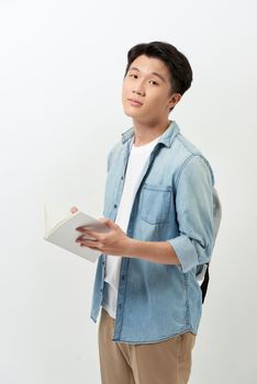 Young Asian man reading book and wearing casual clothing with backpack over white background.