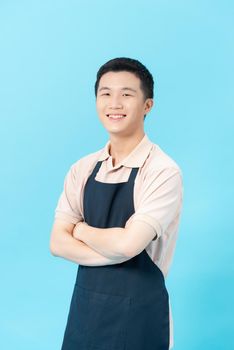 Handsome young man in apron is looking at camera and smiling