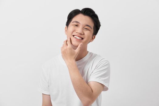 Happy and amazed asian young man touching his face, shocked with unexpected promotion on white background