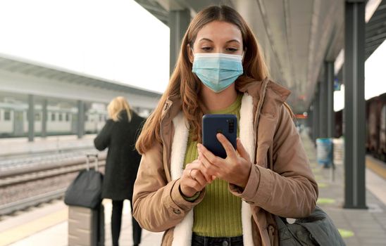 People with surgical mask using smartphone at train station