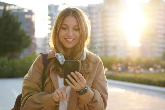 Teenager girl using smartphone outdoor at sunset