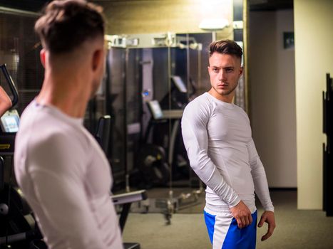 Young Man Admiring His Muscles in Mirror