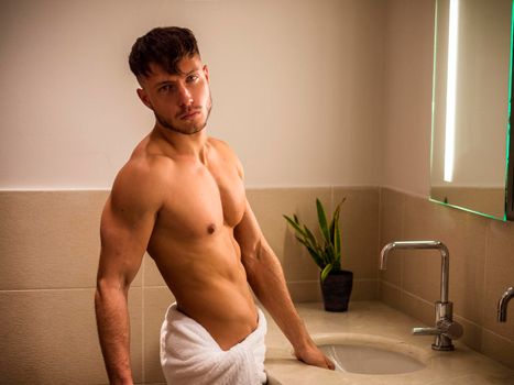 Shirtless young man in bathroom looking at camera