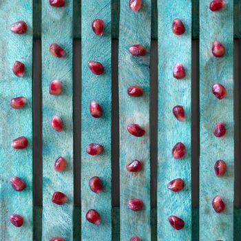 Seamless textured background. Red pomegranate seeds on a turquoise board.