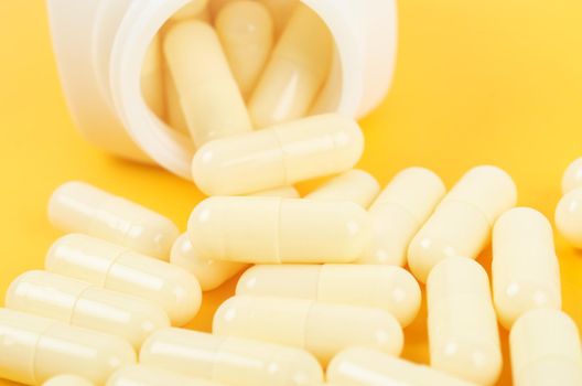Yellow pharmaceutical medicine capsules over yellow background.