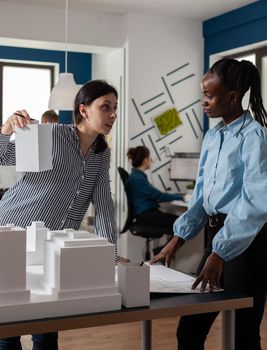Architect presenting foam scale building model to engineer coworker