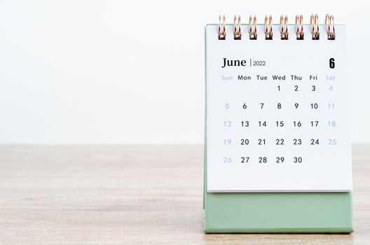 June 2022 desk calendar on wooden table.