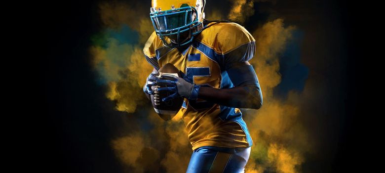 American football player, athlete in helmet with ball on stadium. Sport wallpaper with copyspace.