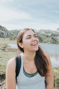 Portrait of young smiling woman with flying hair in windy day standing at mountain - carefree woman, carefree and liberty concepts, bright day