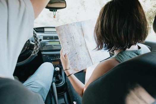 Young hipster couple using a map on a road trip for directions. Reading a map. Cheerful loving couple relaxing on vacation. Trip on route vacation. Happy and smiling to camera. Decision taking