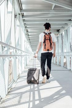 Back view of young man holding hand with grey luggage in the Airport,Travel concept, taking a plane, hurry