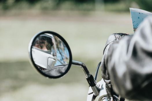 Reflection of a rearview of a motorbike man with a helmet with copy space. On route topic. Travel with safety and using protection while driving.