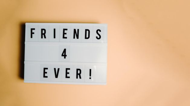 White sign over a pastel orange background, friendship meaning, care and love concepts