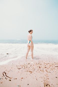 Portrait of a young lady at the beach enjoying warm, tropical ocean water, colorful swimsuit, bright day ocean