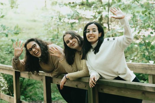 Three young woman saluting to the camera effusively while smiling, friendship and happiness concept