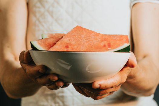 Close up of an old waitress offers and holds a watermelon in a dish, fruits, healthy life, good eating, mediterranean concepts, copy space, vertical image