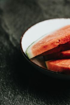 Close up of a dish filled with watermelon over a black marble table, fresh food, wellness, healthy food