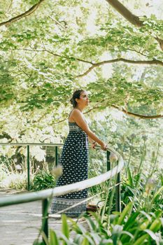 Woman in a forest near a handrail with a dress looking away from camera, liberty freedom anxiety concept, self care, forest ambient
