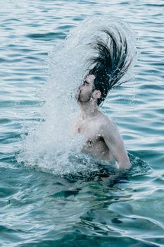 Long hair man inside crystal clear water refreshing his hair, crystal clear water, holiday concept