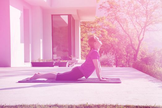 handsome woman doing morning yoga exercises in front of her luxury home villa