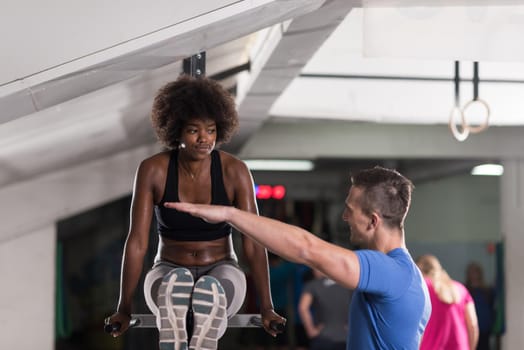 black woman doing parallel bars Exercise with trainer
