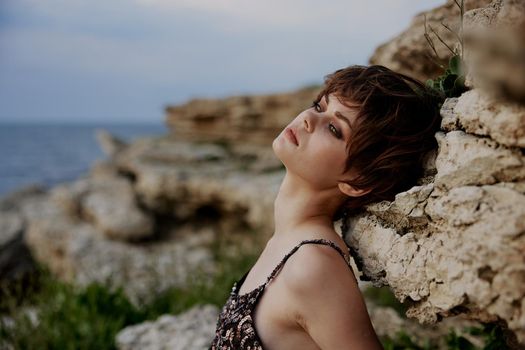 woman with short hair makeup posing on stone rock
