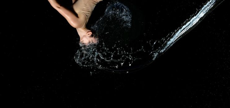 beautiful woman of Caucasian appearance with black hair in drops of water on a black background