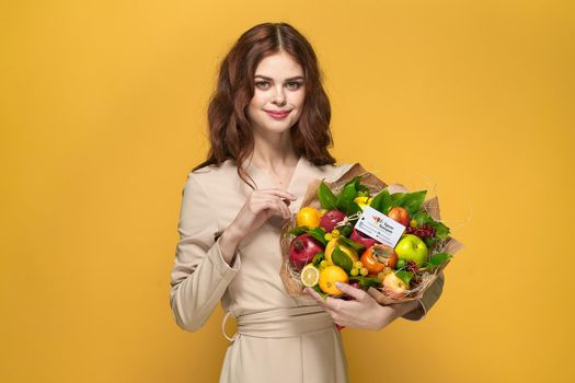 portrait of a woman beige coat fruit bouquet in hands present Studio Model. High quality photo