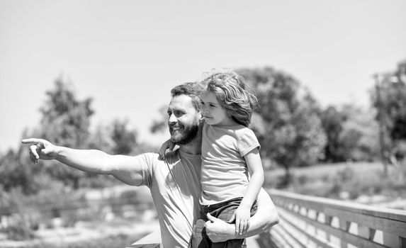 Happy father man hold son child in arms pointing finger summer outdoors, parenting