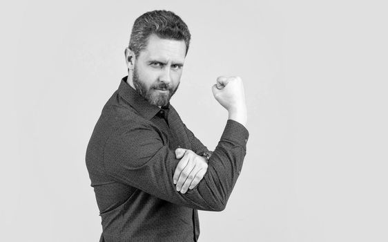 Mature man bend arm in L-shape with fist pointing upwards obscene gesture grey background, fuck you