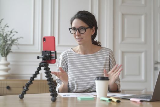 Confident Italian woman economist counselor recording video stream online using smartphone