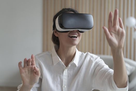 Happy female freelancer wearing VR headset while working remotely online from home