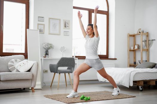 Young fitness girl doing sport exercises at her living room at home, close up