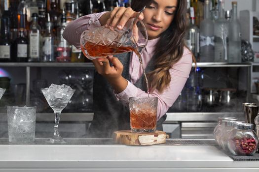 Woman preparing cocktail at bar counter