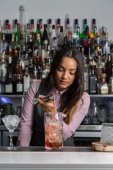 Professional female mixologist preparing cocktail in bar