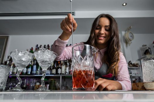 Female bartender stirring alcoholic cocktail