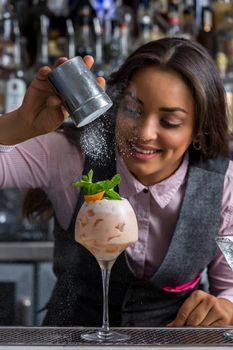 Optimistic female bartender preparing sweet cocktail