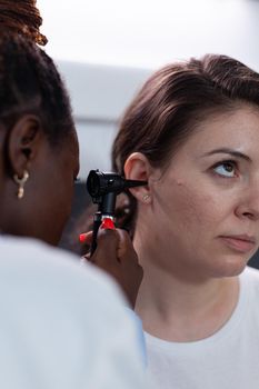 Closeup of african american otologist doctor analyzing woman patient ear