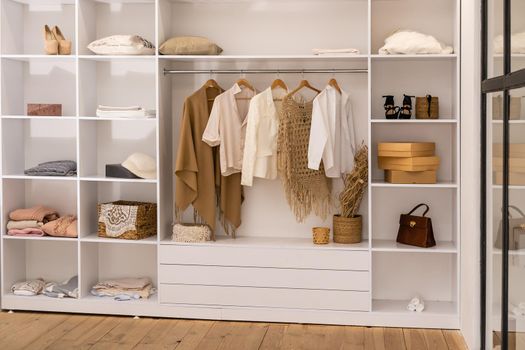 clothes hanging on rail in white wardrobe with boxes