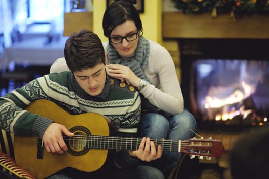 Young romantic couple sitting and relaxing in front of fireplace at home