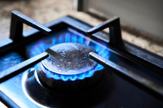 Cooker as heater. Blue flame from gas hob produce greenhouse gas emissions. Wastage of natural resources. Kitchen stove grate on a burner fuelled by combustible natural gas or syngas, propane, butane.