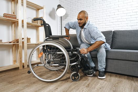 Black disabled man sits down on wheelchair at home