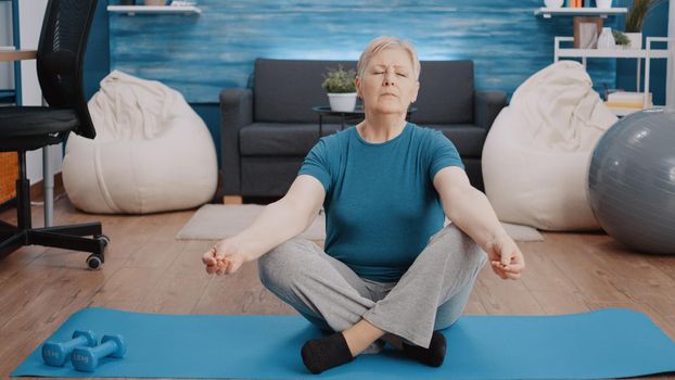 Retired woman with closed eyes sitting in lotus position