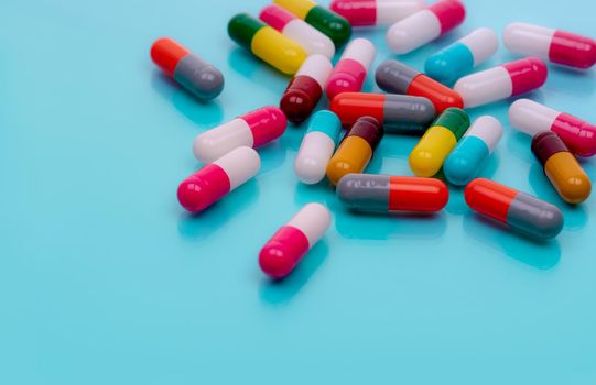 Antibiotic capsule pills on blue background. Prescription drugs. Colorful capsule pills. Antibiotic drug resistance concept. Pharmaceutical industry. Superbug problems. Medicament and pharmacology.