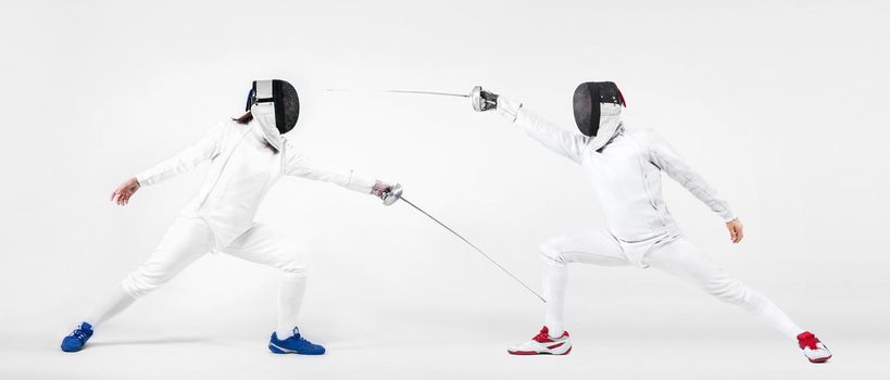 Young fencer athlete wearing mask and white fencing costume. holding the sword. Isolated on white background