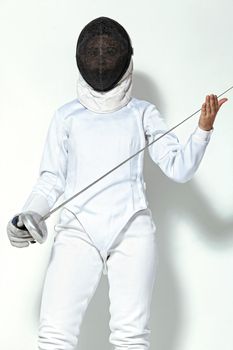 Young fencer athlete wearing fencing costume and mask holding the sword. Isolated on white background