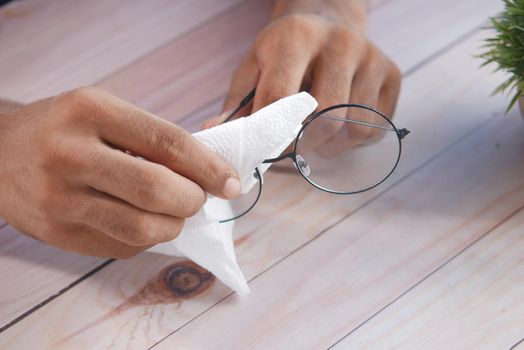 Close up of man hand cleaning eyeglass