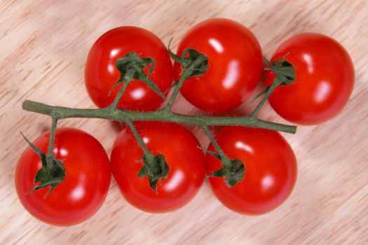 six tomatoes on the vine on a wood chopping board