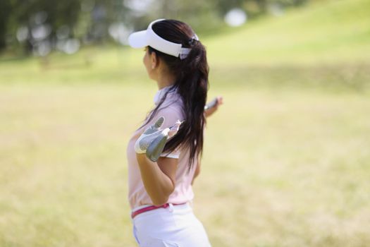 Professional woman golf player pose with golf club on field