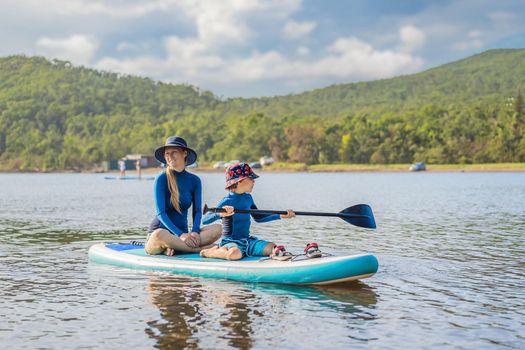 happy family of two, mother and son, enjoying stand up paddling during summer vacation
